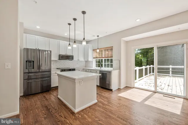 a kitchen with stainless steel appliances granite countertop a refrigerator a stove a sink dishwasher and a oven with wooden floor