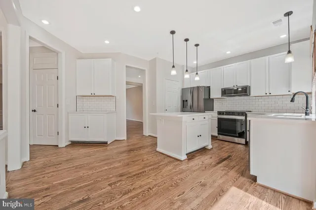 an empty room with windows a fireplace and wooden floor