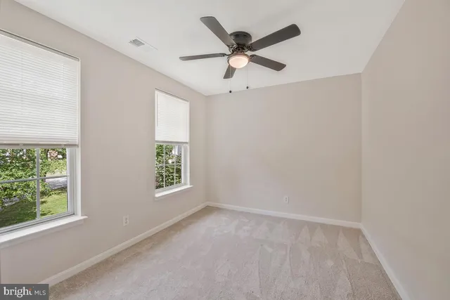an empty room with a window and a fan