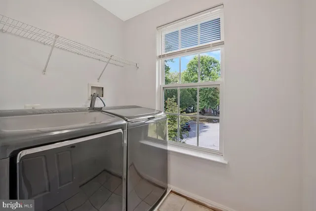 a view of an empty room with wooden floor kitchen view and a window
