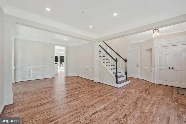 a view of an empty room with wooden floor and stairs
