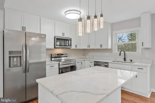 a kitchen with stainless steel appliances granite countertop a sink a stove and a refrigerator