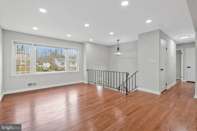 a view of an empty room with a window and wooden floor