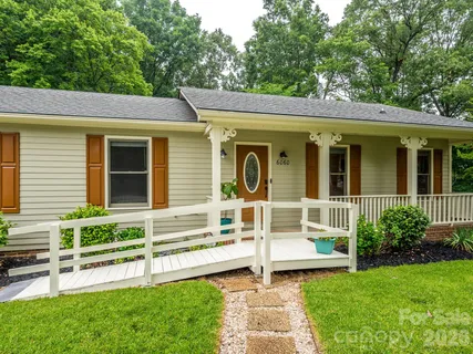 a view of a house with a yard porch and a large tree