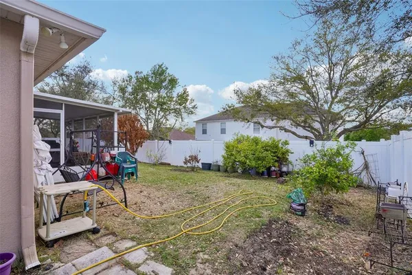 a backyard of a house with plants and large tree