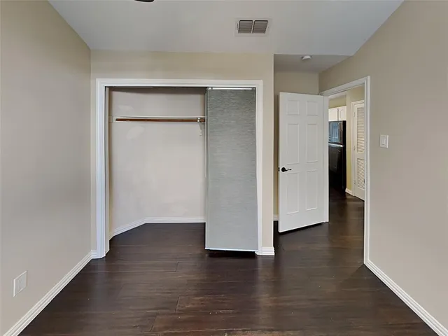 an empty room with wooden floor & cabinet and a bathroom