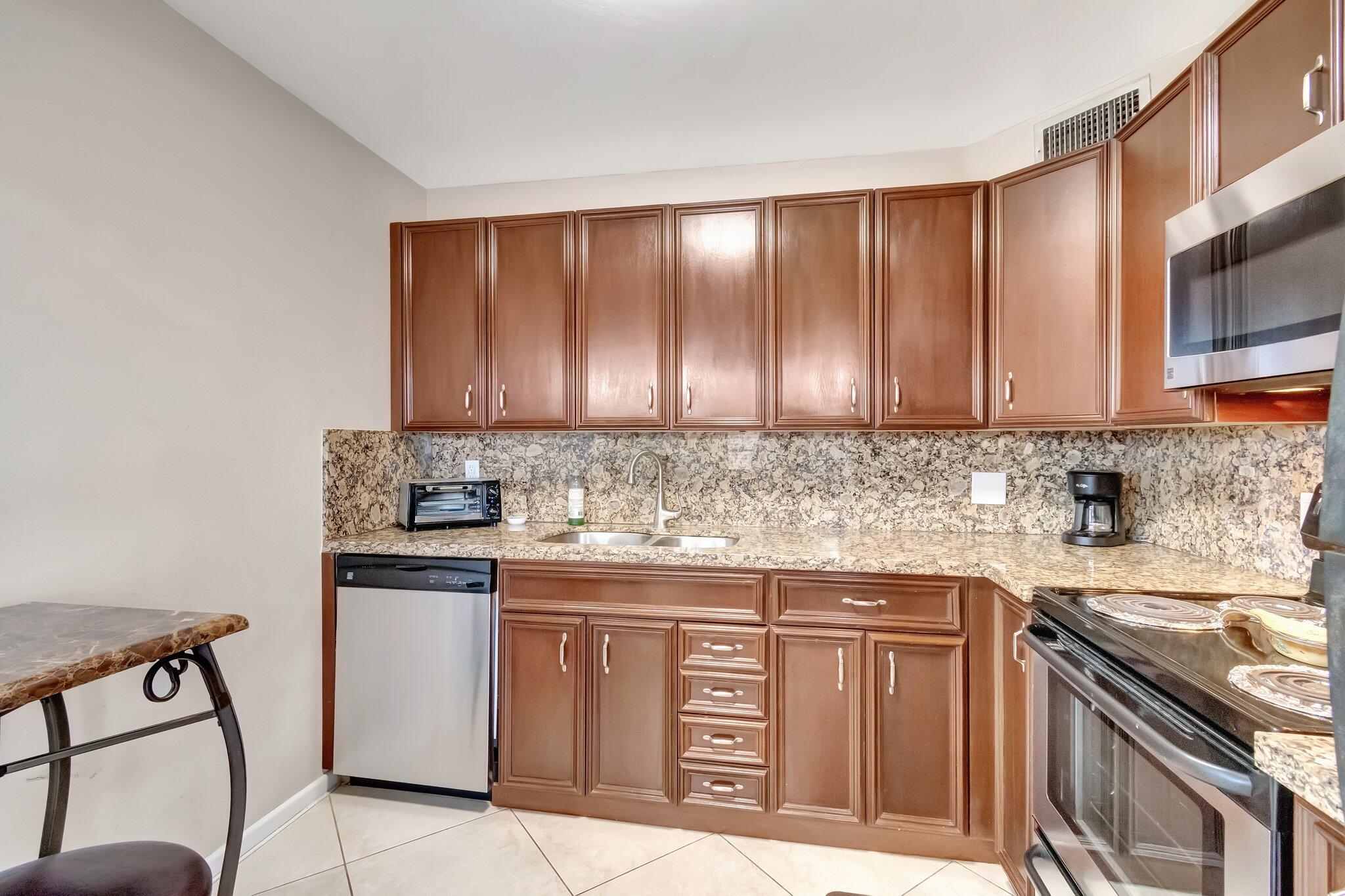 4049 Wolverton C Boca Raton, FL 33434 - Photo 16 of 88 a kitchen with stainless steel appliances granite countertop a stove a sink and a microwave