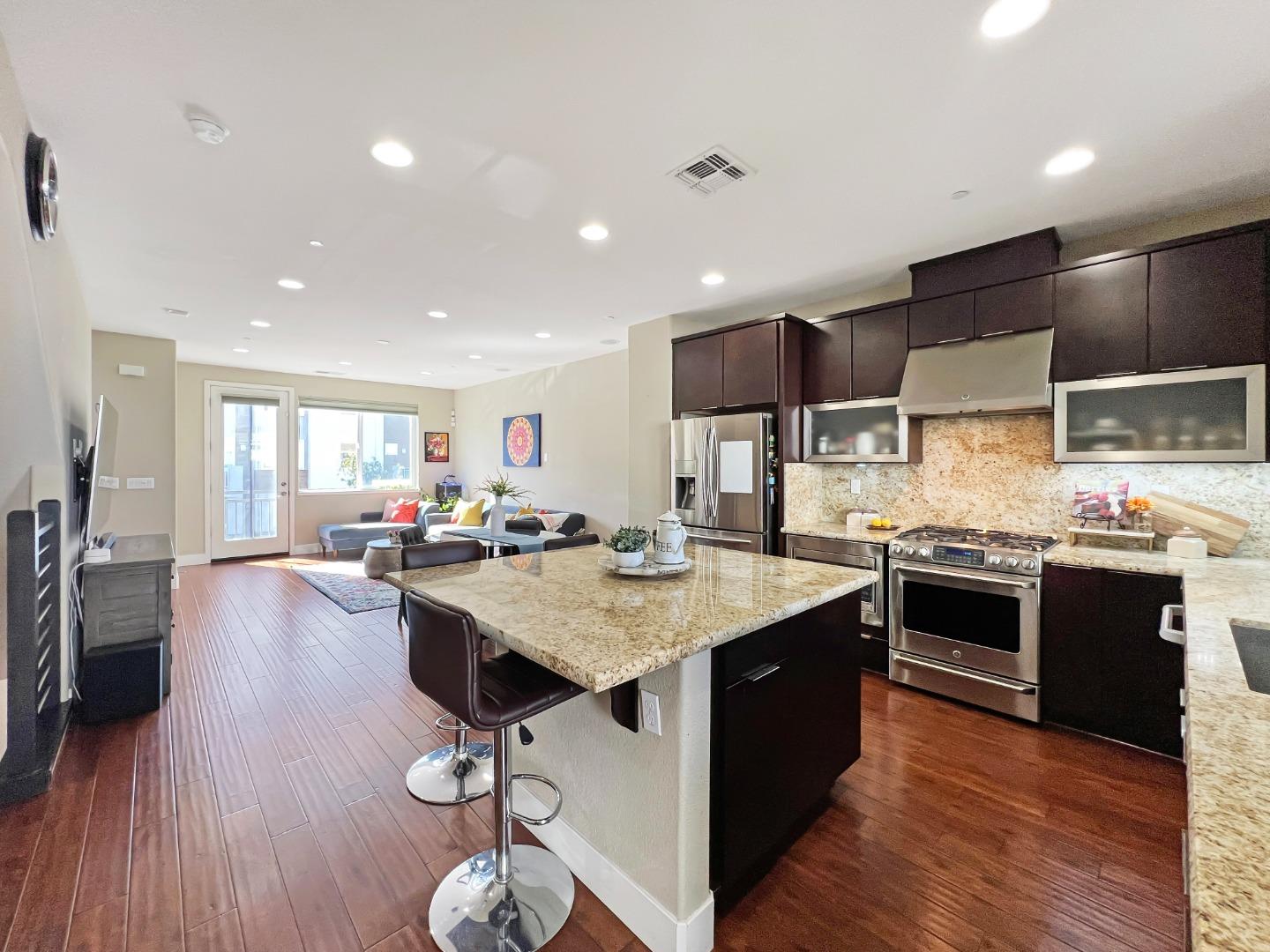 a large kitchen with stainless steel appliances a stove a sink dishwasher and a dining table with wooden floor