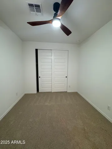 an empty room with ceiling fan and window