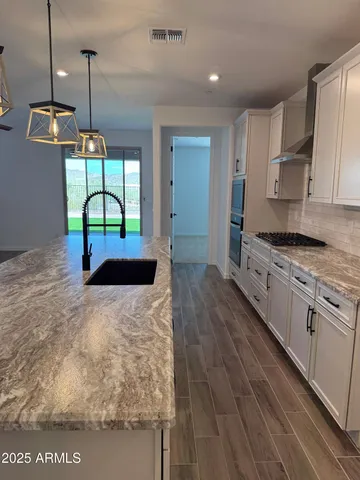 a kitchen with stainless steel appliances granite countertop a sink a stove top oven a counter space and cabinets