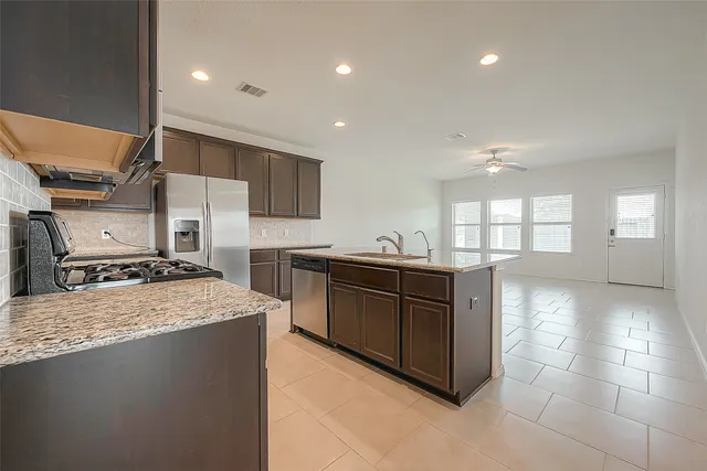 a kitchen with stainless steel appliances granite countertop a stove a sink and a refrigerator