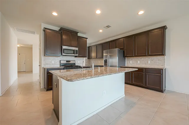 a kitchen with stainless steel appliances granite countertop a stove top oven a sink and a refrigerator
