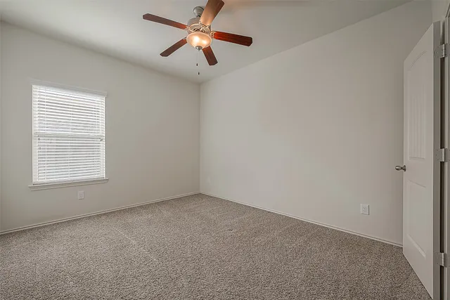 a view of an empty room and chandelier fan