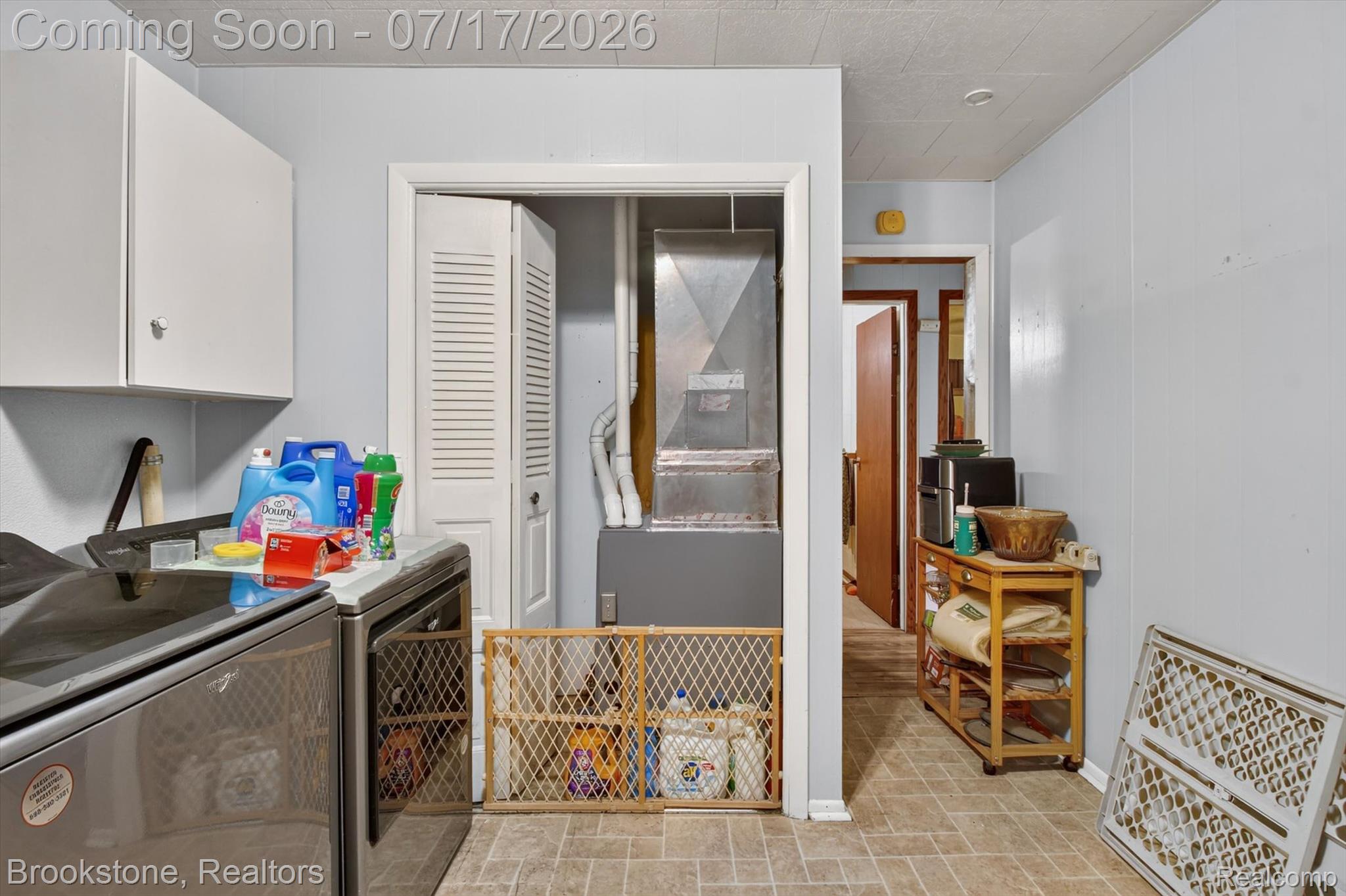 22709 Pleasant Valley Road Hillman, MI 49746 - Photo 22 of 42 Laundry area featuring a utility closet with bifold louvered doors, light blue wall paneling, and vinyl flooring
