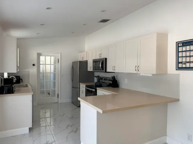 a kitchen with white cabinets and sink