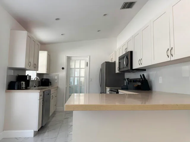 a kitchen with white cabinets and stainless steel appliances