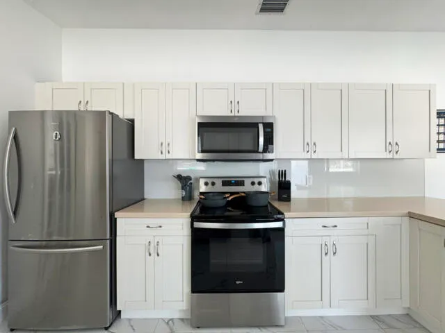 a kitchen with stainless steel appliances a stove a refrigerator a sink a counter space and cabinets