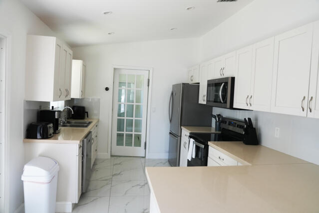 9420 Nickels Boulevard Boynton Beach, FL 33436 - Photo 21 of 57 a kitchen with stainless steel appliances a stove a refrigerator a sink a counter space and cabinets