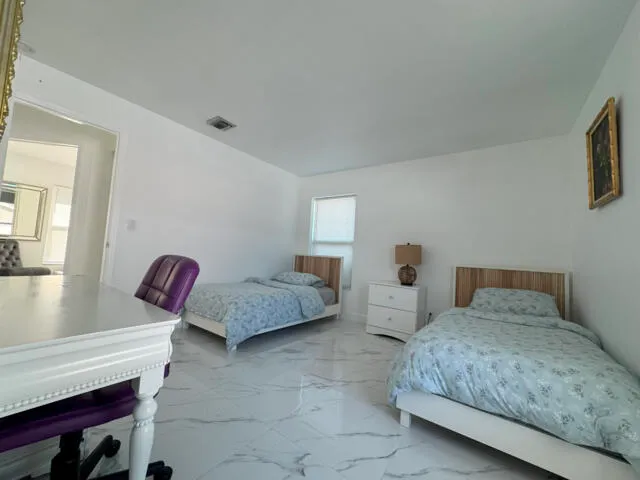 a bedroom with a large bed and a lamp on dresser