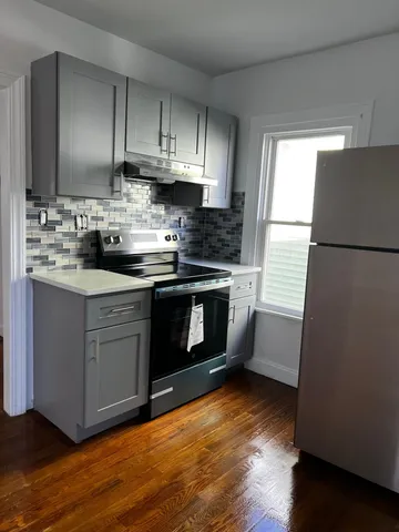 a kitchen with stainless steel appliances granite countertop a stove a refrigerator a sink a stove a microwave and wooden floors