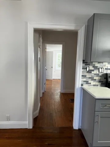 a hallway view with wooden floor and electronic appliances