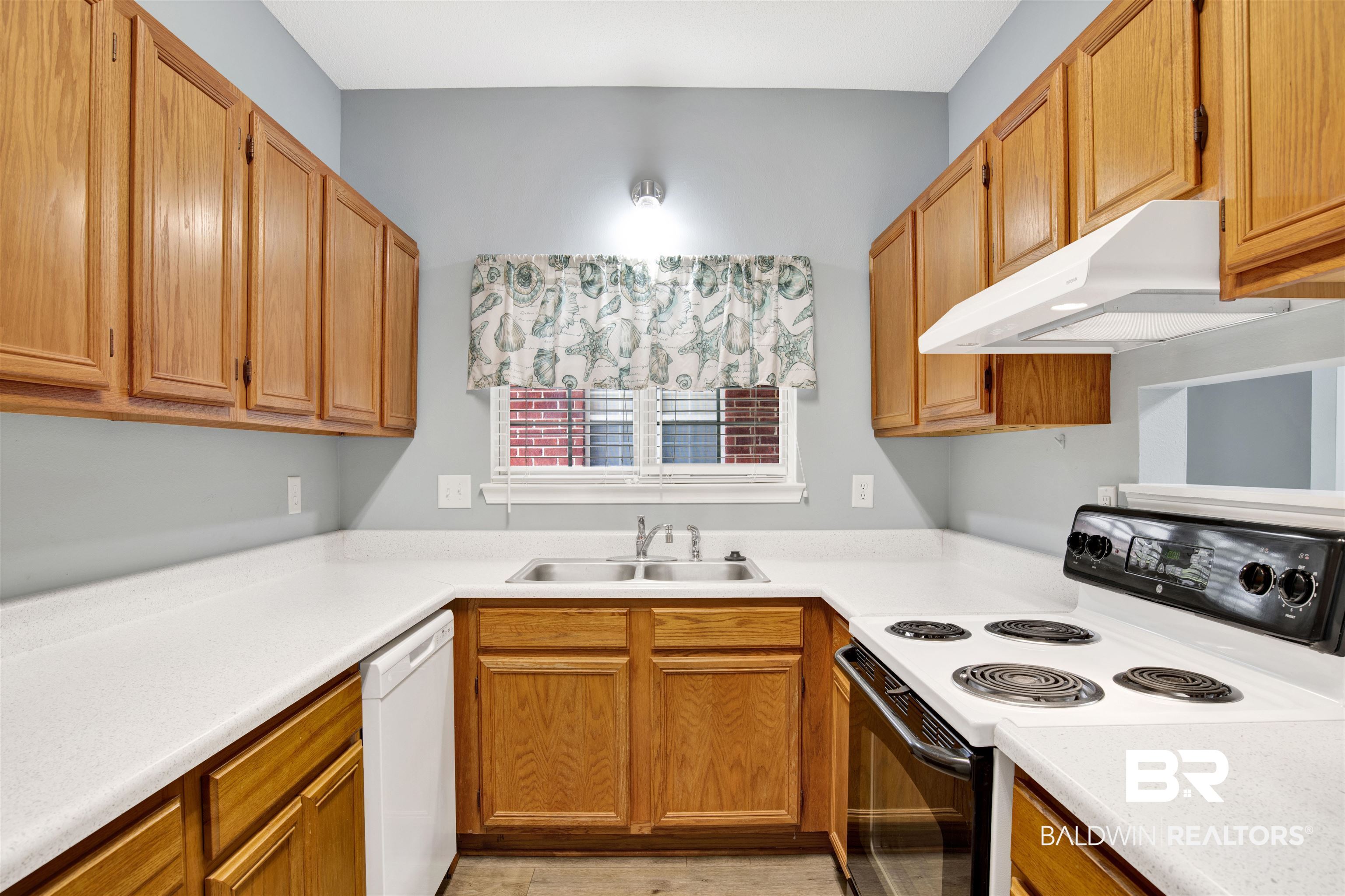 1258 Sutton Court, Unit 4 Mobile, AL 36609 - Photo 8 of 19 Kitchen with light countertops, under cabinet range hood, a sink, dishwasher, and range with electric cooktop