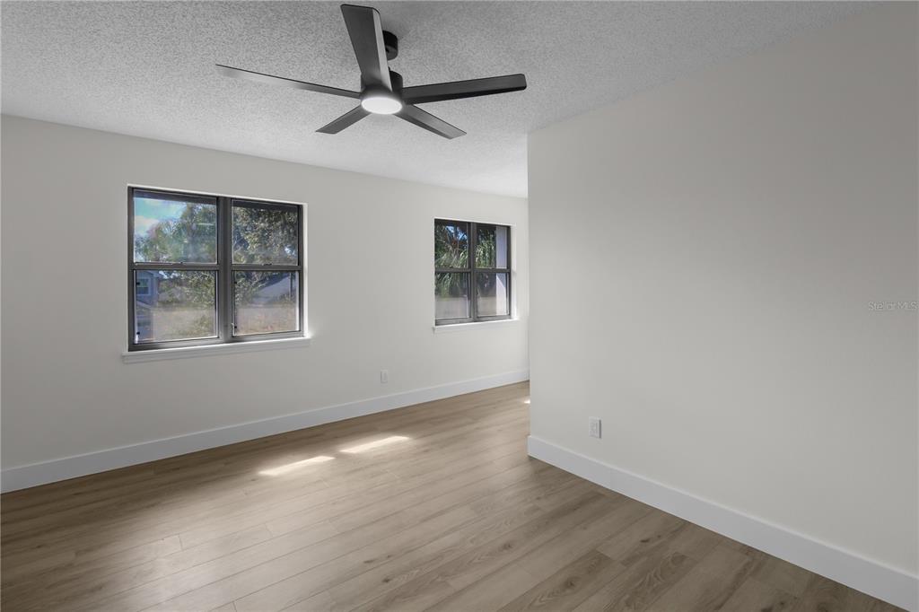 1888 Springbush Lane Clearwater, FL 33763 - Photo 18 of 31 an empty room with wooden floor ceiling fan and windows