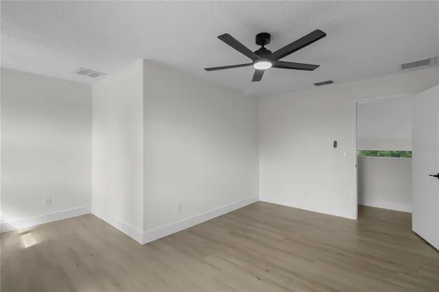 an empty room with wooden floor and a ceiling fan