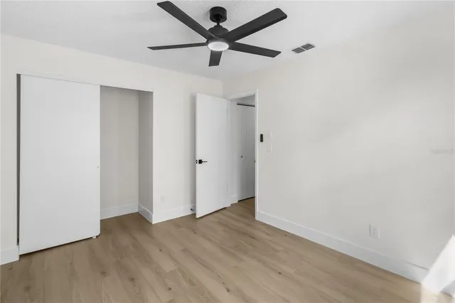 an empty room with wooden floor and a ceiling fan