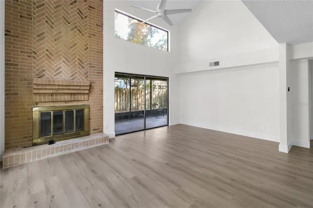 an empty room with wooden floor fireplace and windows
