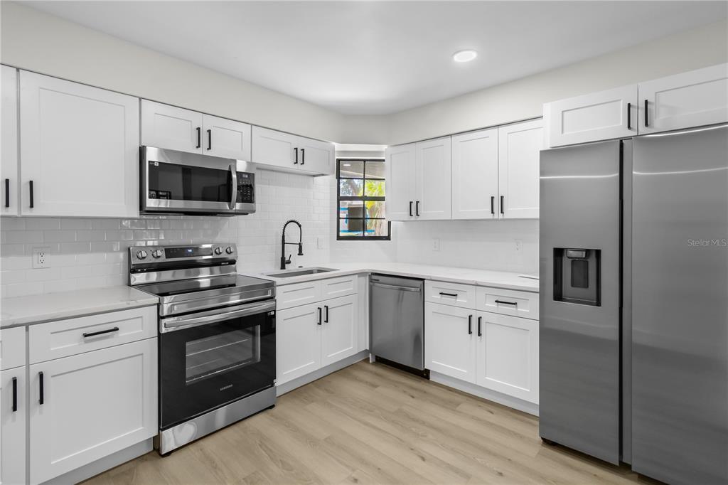 1888 Springbush Lane Clearwater, FL 33763 - Photo 9 of 31 a kitchen with cabinets stainless steel appliances and wooden floor