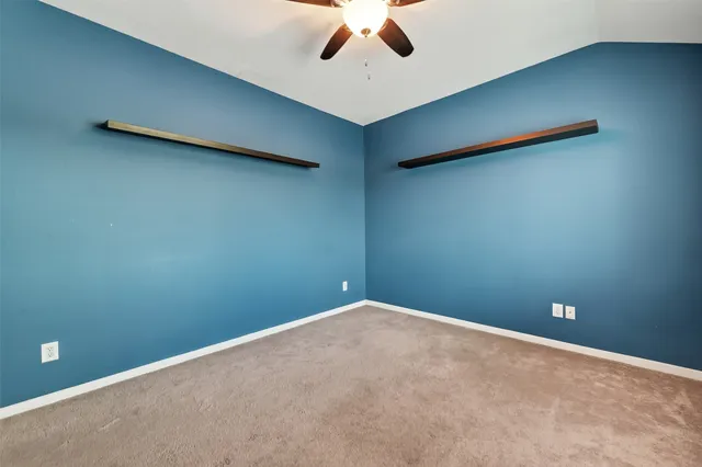 an empty room with a ceiling fan and carpet