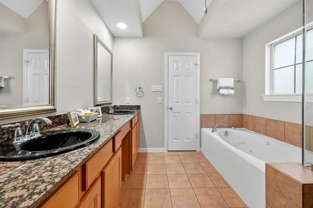 a bathroom with a tub sink a mirror a vanity and window
