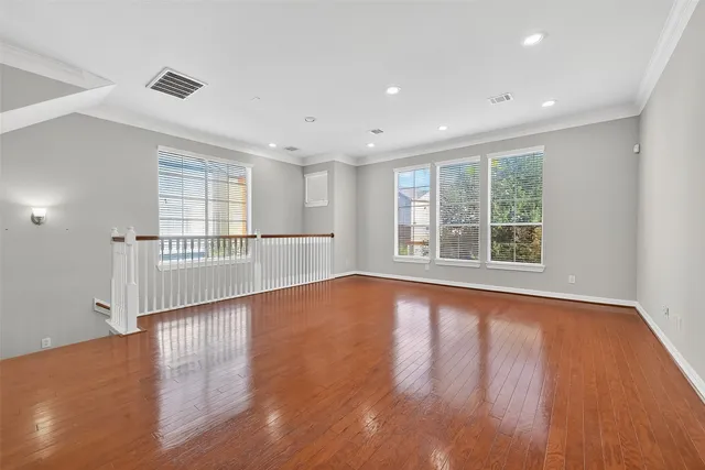 a view of empty room with wooden floor and fan