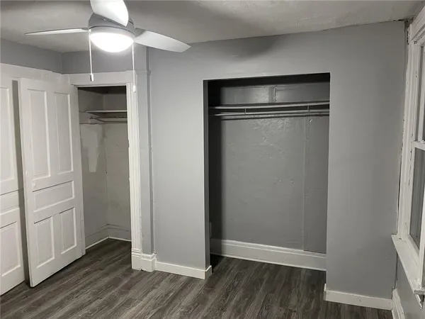 an empty room with wooden floor closet and windows