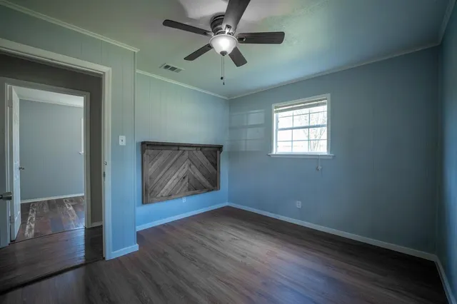 an empty room with wooden floor chandelier fan and windows