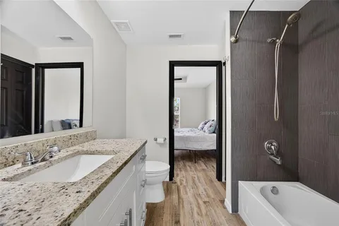 a bathroom with a granite countertop sink a mirror and bathtub