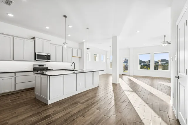 a kitchen with stainless steel appliances granite countertop a sink a stove and a wooden floors