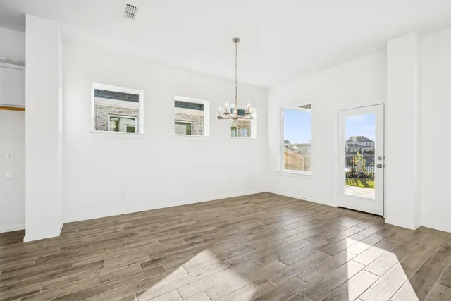 a view of an empty room with window and wooden floor