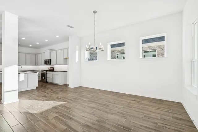 a view of an empty room with window and wooden floor