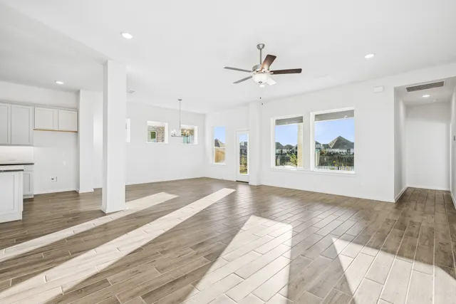 a view of an empty room with window and wooden floor