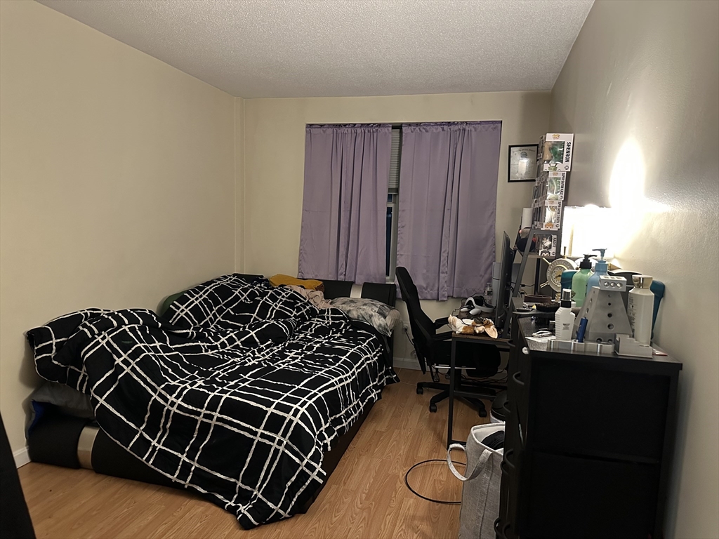 605 Eastern Avenue, Unit 211 Lynn, MA 01902 - Photo 16 of 29 a bed sitting in a bedroom next to a cabinet and mirror