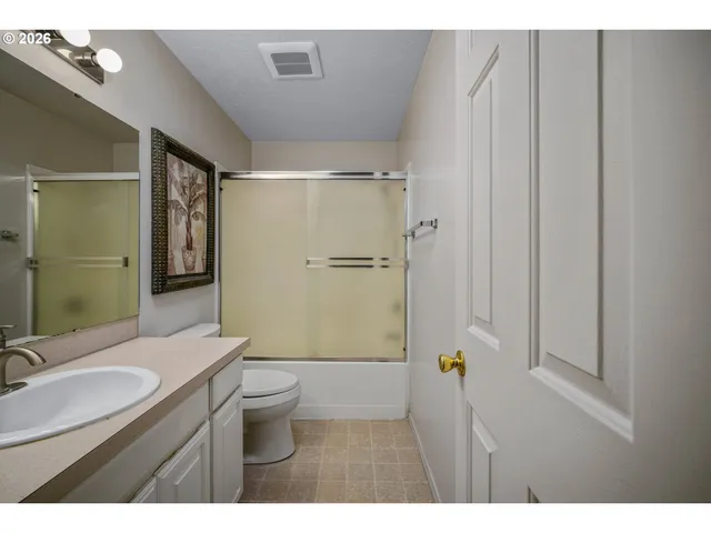 a bathroom with a granite countertop sink a mirror a toilet and shower