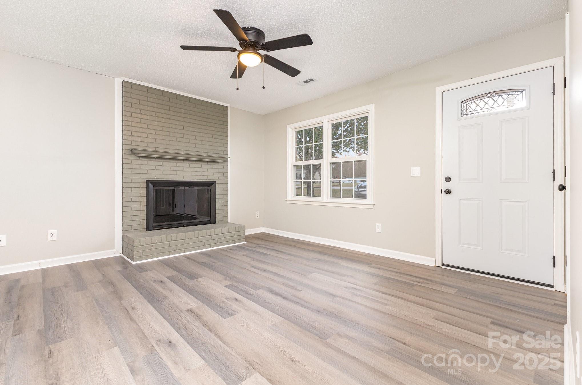 132 Hicks Road Grover, NC 28073 - Photo 9 of 31 an empty room with wooden floor a ceiling fan and windows