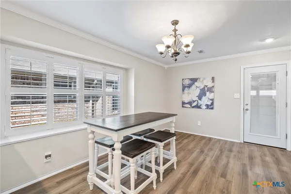 a view of a dining room with furniture a chandelier and wooden floor
