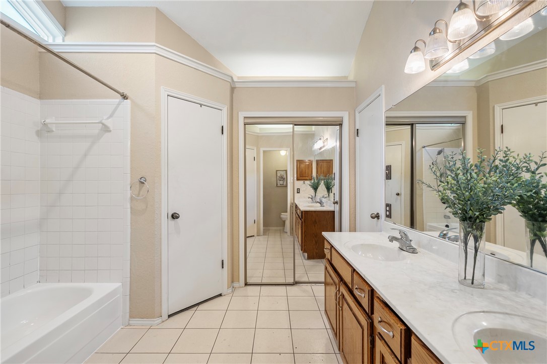 4518 Stagecoach Trail Temple, TX 76502 - Photo 20 of 29 a bathroom with a granite countertop sink a mirror and a bathtub