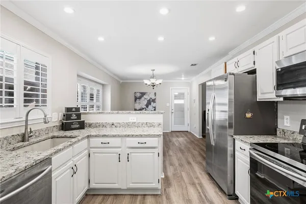 a kitchen with granite countertop a sink stainless steel appliances and cabinets