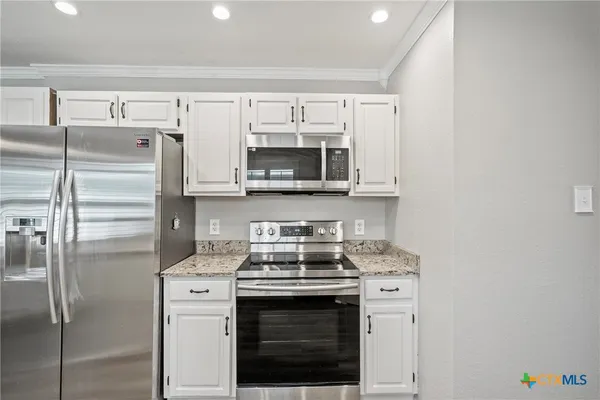 a kitchen with stainless steel appliances white cabinets and a stove top oven