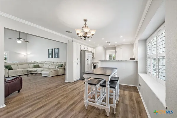 a view of a dining room and livingroom with furniture wooden floor a chandelier