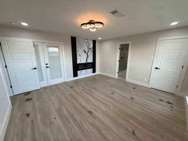 a large kitchen with stainless steel appliances a large counter top a wooden floor a stove a bathtub and next to a window